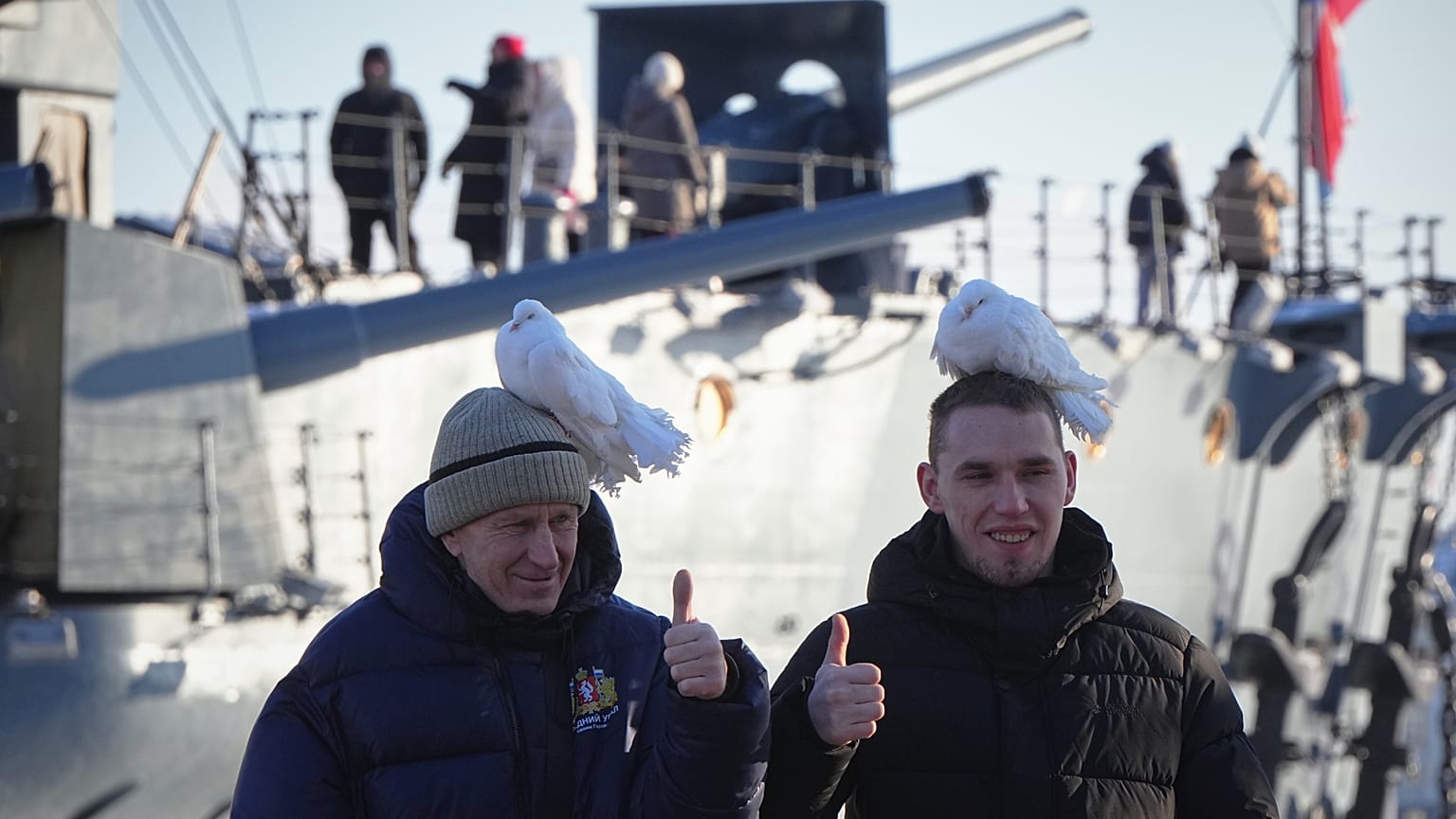 Мужчины позируют с белыми голубями у крейсера “Аврора” в Санкт‑Петербурге, Россия, суббота, 31 января 2026 года