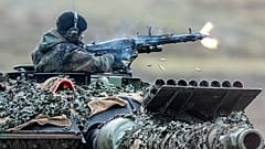 Titel: Deutsch-ukrainische Rüstungsindustrie. Ein Soldat feuert ein Maschinengewehr aus einem Leopard-2-Panzer.