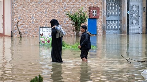 Şiddetli yağışın ardından Fas’ın Ksar El Kebir kentinde su basmış bir caddeden tahliye edilen bir anne ve oğlu, 30 Ocak 2026