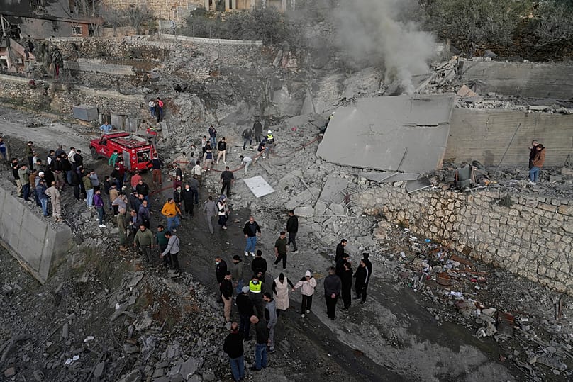 عناصر من الدفاع المدني ومدنيون يتجمعون قرب مبنى دمّره قصف إسرائيلي في بلدة عين قانا جنوب لبنان، في 2 فبراير 2026.