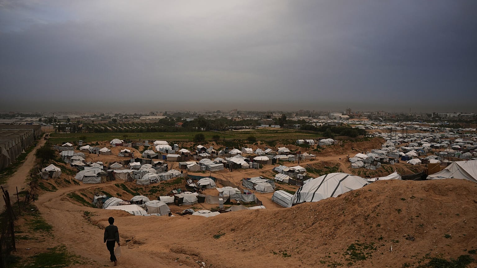 طفل يمرّ بجوار خيام تؤوي فلسطينيين نازحين في دير البلح، وسط قطاع غزة، الأحد 1 فبراير/شباط 2026. (تصوير: عبد الكريم هنا / أسوشييتد برس)