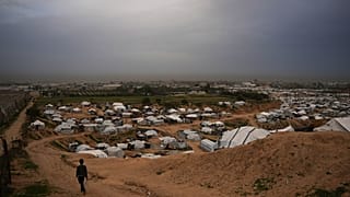 طفل يمرّ بجوار خيام تؤوي فلسطينيين نازحين في دير البلح، وسط قطاع غزة، الأحد 1 فبراير/شباط 2026. (تصوير: عبد الكريم هنا / أسوشييتد برس)