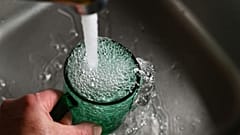 Auf diesem Foto läuft Wasser aus dem Hahn in ein Glas.
