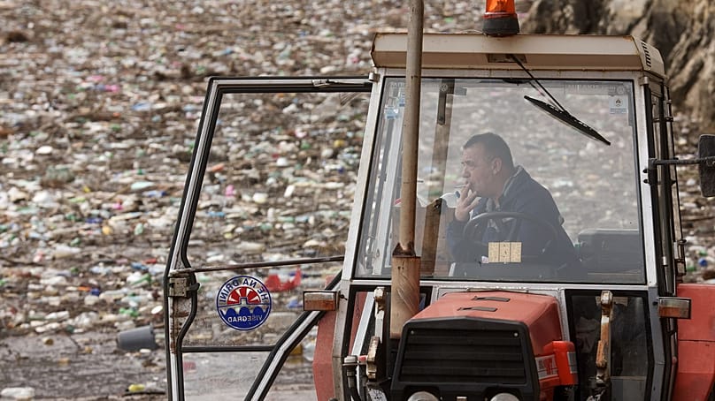 یک کارگر در حال استراحت است و در پس‌زمینه، ده‌ها تن زباله شناور دیده می‌شود که در نتیجه مسدود شدن رود درینا در ویشگراد بوسنی روی آب جمع شده است؛ پنجشنبه ۵ فوریه ۲۰۲۶.
