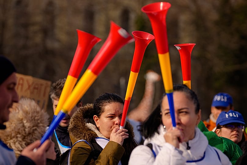 A woman blows into a vuvuzela as teachers and education system employees take part in a protest against planned austerity measures, 