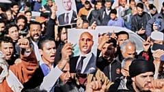  ليبيون يسيرون لحضور جنازة سيف الإسلام، نجل الزعيم الليبي الراحل معمر القذافي، حاملين صورة والده في مدينة بني وليد، ليبي��، الجمعة 6 فبراير/شباط 2026. 