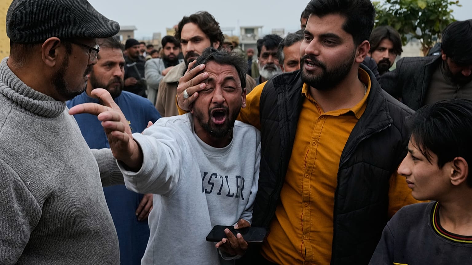 يواسي أشخاص رجلاً، في الوسط، ناعيًا على وفاة أحد أقاربه، بالقرب من موقع انفجار قنبلة في مسجد شيعي بإسلام آباد، باكستان، يوم الجمعة، 6 فبراير 2026. 