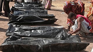 أقارب يتحققون من أسماء ضحايا الصراع السوداني المستمر منذ عامين على أكياس الجثث، بعد أن نقلت جمعية الهلال الأحمر السوداني الرفات من المقابر المؤقتة إلى مقبرة محلية في الخرطوم،