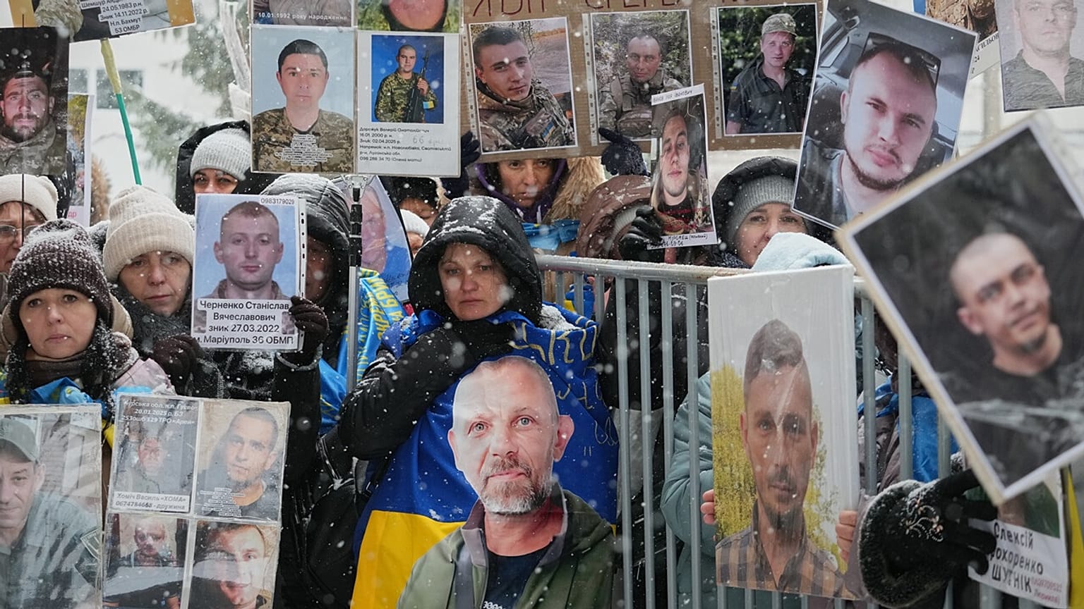 People hold photos of their missing relatives as Ukrainian soldiers return from captivity during a POW exchange between Russia and Ukraine in Chernyhiv region, Feb. 5, 2026.