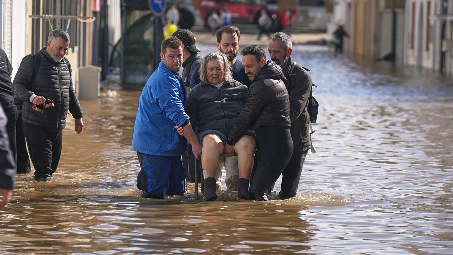 Iria Afonso, 76 anos, é carregada numa cadeira pelos vizinhos enquanto é evacuada da sua casa inundada após fortes chuvas terem causado o transbordamento do rio Sado