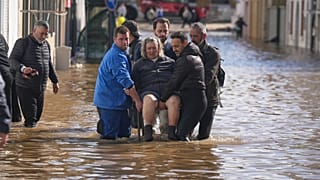 Iria Afonso, 76 anos, é carregada numa cadeira pelos vizinhos enquanto é evacuada da sua casa inundada após fortes chuvas terem causado o transbordamento do rio Sado