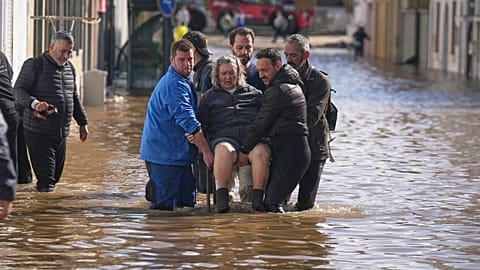 Iria Afonso, 76, is carried on a chair by neighbours as she is evacuated from her flooded house after heavy rains caused the river Sado to overflow its banks.