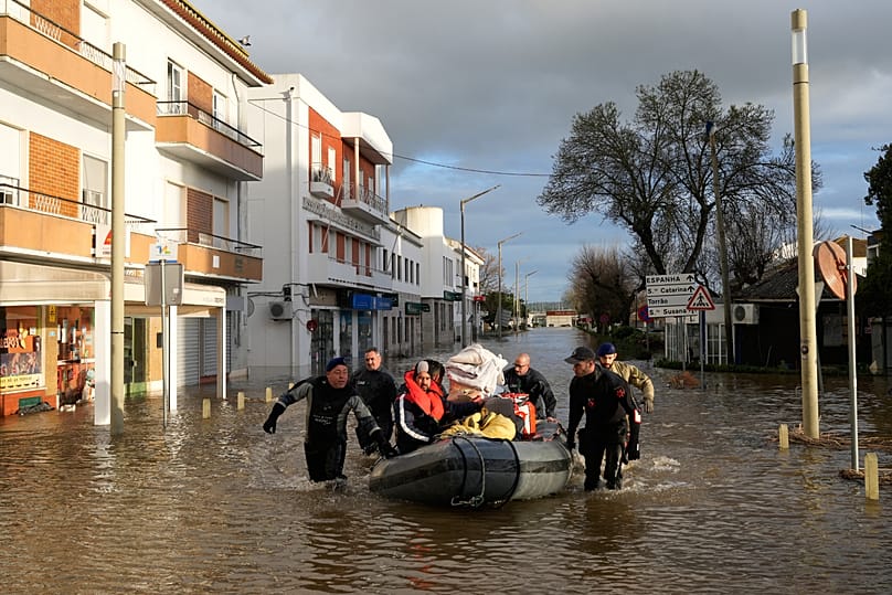 Policiais e fuzileiros navais evacuam residentes de um hotel em barcos infláveis ao longo de uma rua inundada após o transbordamento do rio Sado, causado por fortes chuvas