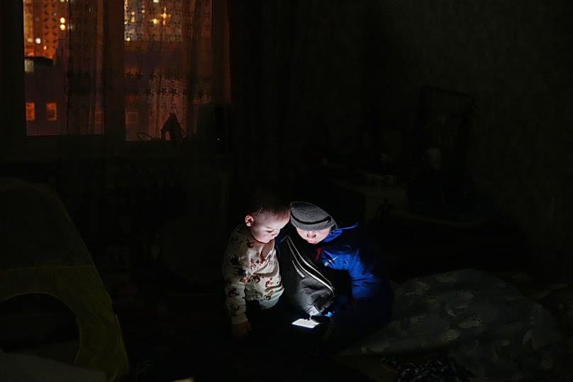 Der 11-jährige Daniil Dolotov spielt während eines Stromausfalls mit seinem 18 Monate alten Bruder Bohdanchyk in ihrer Wohnung auf einem Handy. 