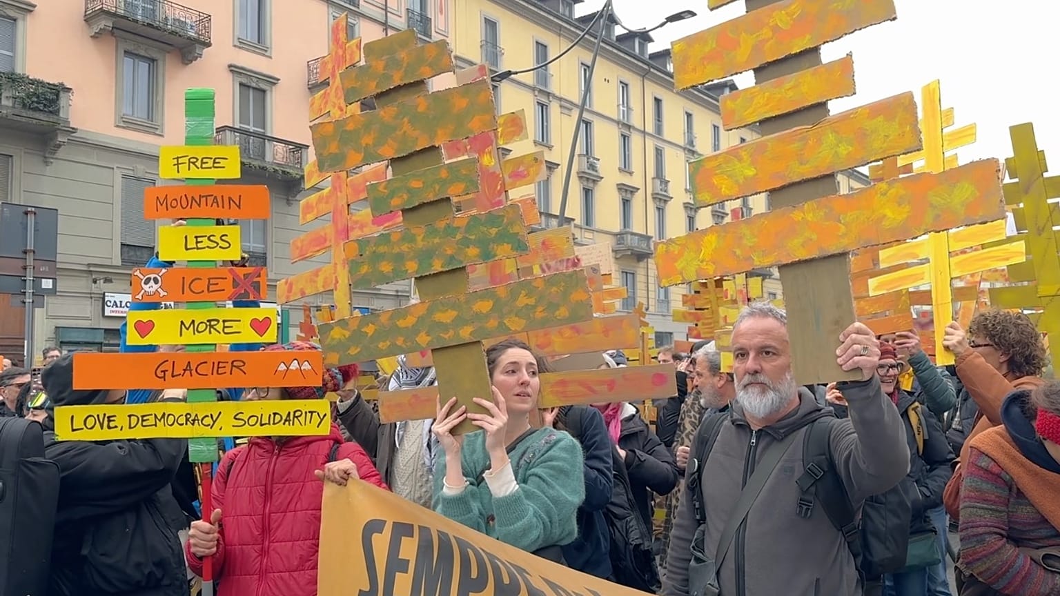 People protesting against the environmental and economic unsustainability of the 2026 Milan-Cortina Winter Olympics holding up signs in Milan on 7 February 2026.