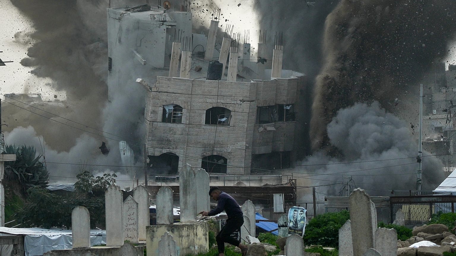 رجل يركض طلبًا للملاذ في مقبرة بينما يتصاعد الدخان جراء غارة عسكرية إسرائيلية على أحد المباني في حي الزيتون بمدينة غزة، يوم الجمعة 6 فبراير 2026. 