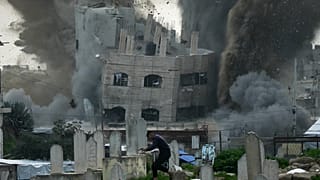 رجل يركض طلبًا للملاذ في مقبرة بينما يتصاعد الدخان جراء غارة عسكرية إسرائيلية على أحد المباني في حي الزيتون بمدينة غزة، يوم الجمعة 6 فبراير 2026. 