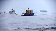FILE - An Icebreaker makes the path for a cargo ship with an iceberg in the background near a port on the Alexandra Land island near Nagurskoye, Russia, May 17, 2021. 