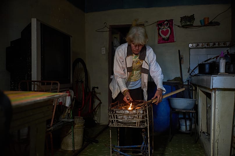 Minorkys Hoyos Ruiz lights coals to cook dinner during a scheduled blackout to ration energy in Santa Cruz del Norte, late afternoon Tuesday, Feb. 3, 2026. 