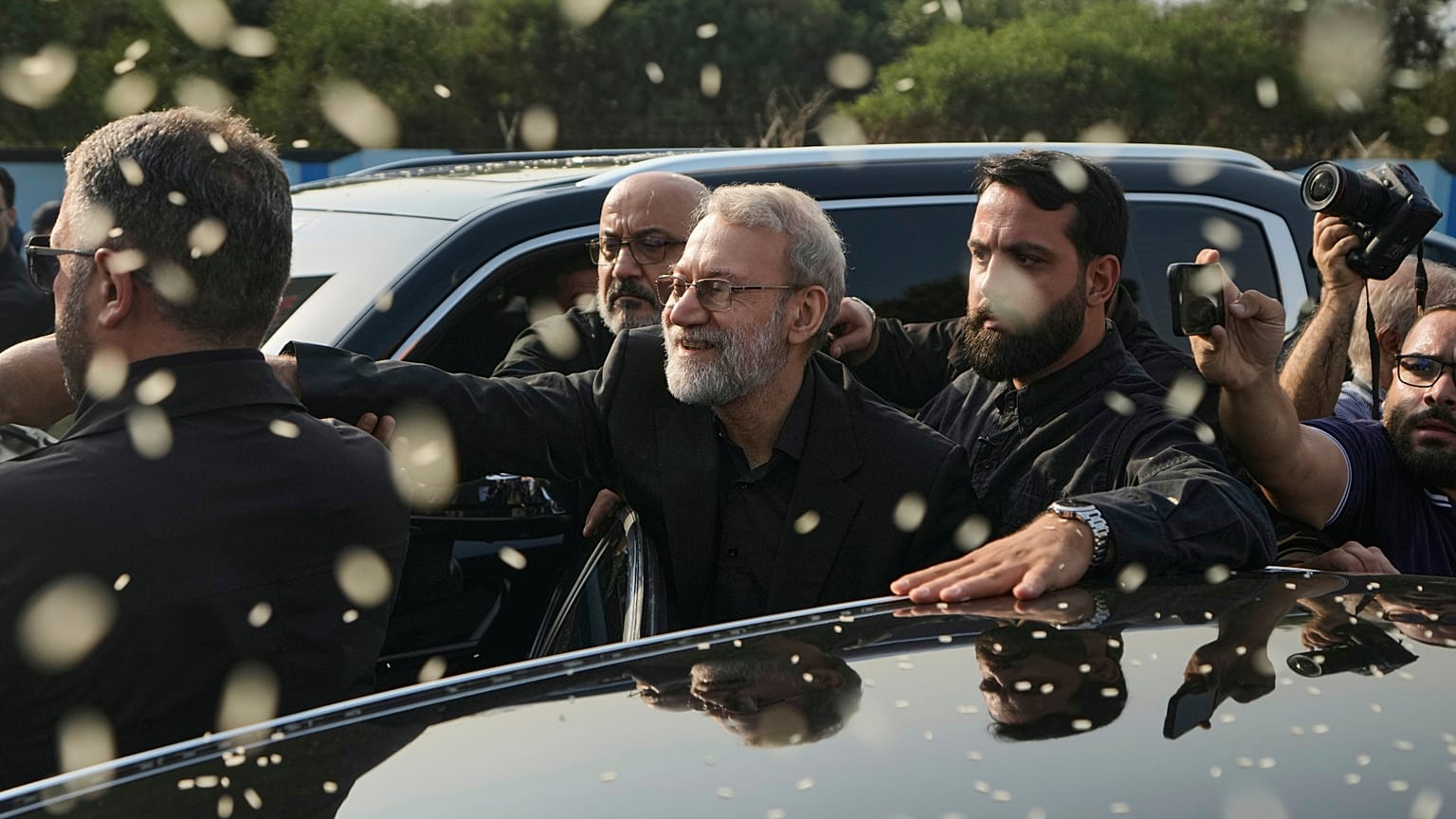 صورة أرشيفية - علي لاريجاني، في الوسط، سكرتير المجلس الأعلى للأمن القومي الإيراني، يلوّح بيده بينما يقوم أنصار حزب الله برمي الأرز للترحيب به خارج مطار رفيق الحريري الدولي في 