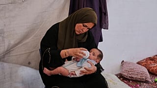 فلسطينية تُطعِم ابنتها في مخيم خان يونس، 15 مايو 2025.