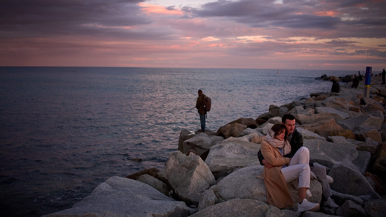 Dos turistas franceses observan una puesta de sol en un muelle de Barcelona, frente a la costa mediterránea, el 8 de febrero de 2026