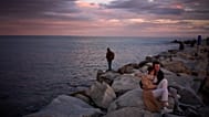 Dos turistas franceses observan una puesta de sol en un muelle de Barcelona, frente a la costa mediterránea, el 8 de febrero de 2026
