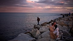 Zwei französische Touristen beobachten am 8. Februar 2026 einen Sonnenuntergang auf einem Pier in Barcelona an der Mittelmeerküste.
