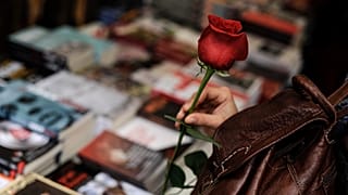 İspanya'nın kuzeyindeki Pamplona şehrinde, Uluslararası Kitap Günü'nde bir kadın elinde kırmızı bir gül tutarken kitaplara bakıyor, 23 Nisan 2014.