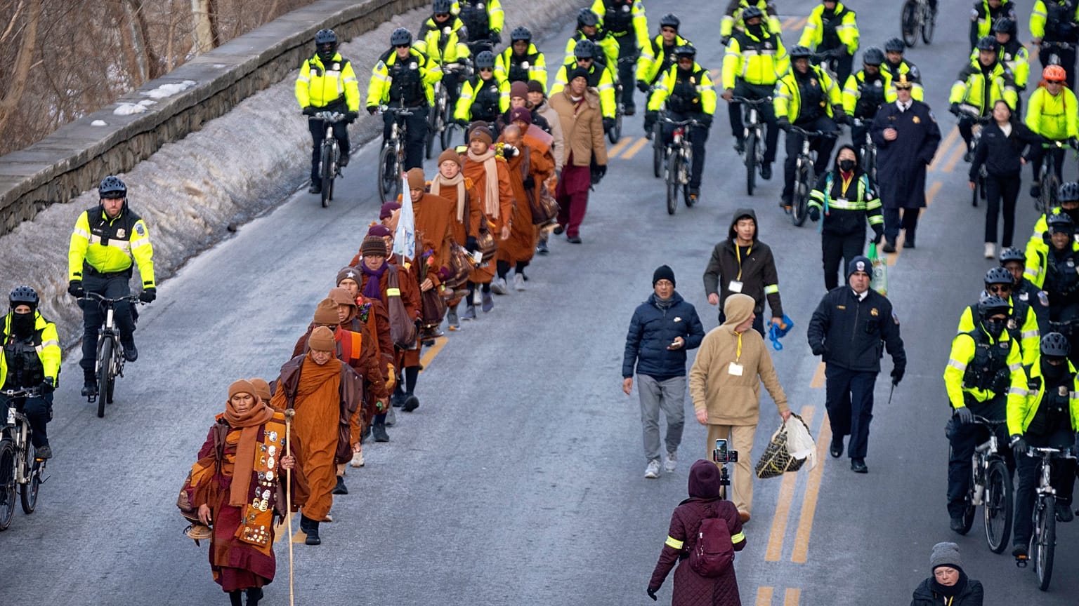 Buddhist monks who are participating in a Walk For Peace are escorted by Metropolitan Police officers as they walk along the C&O Canal and Potomac River on Tuesday, Feb. 10