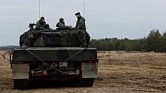Soldados ucranianos e polacos sentados em cima de um tanque Leopard 2 durante um treino numa base militar e campo de testes em Swietoszow, na Polónia, a 13 de fevereiro de 2023. 