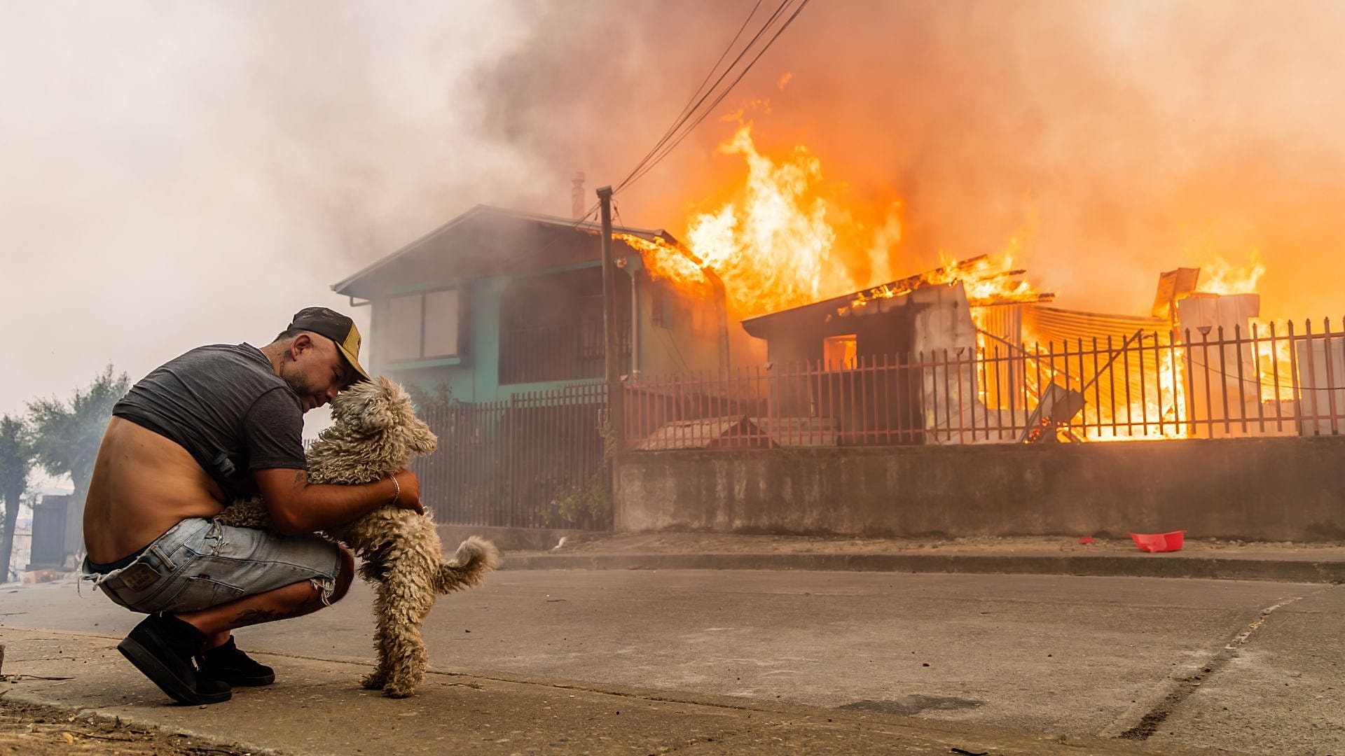 ARCHÍV FELVÉTEL - Manuel Lagos megsimogatja kutyáját, miközben otthonukat elnyeli a közeledő bozóttűz a chilei Lirquénben, 2026. jan. 18-án.