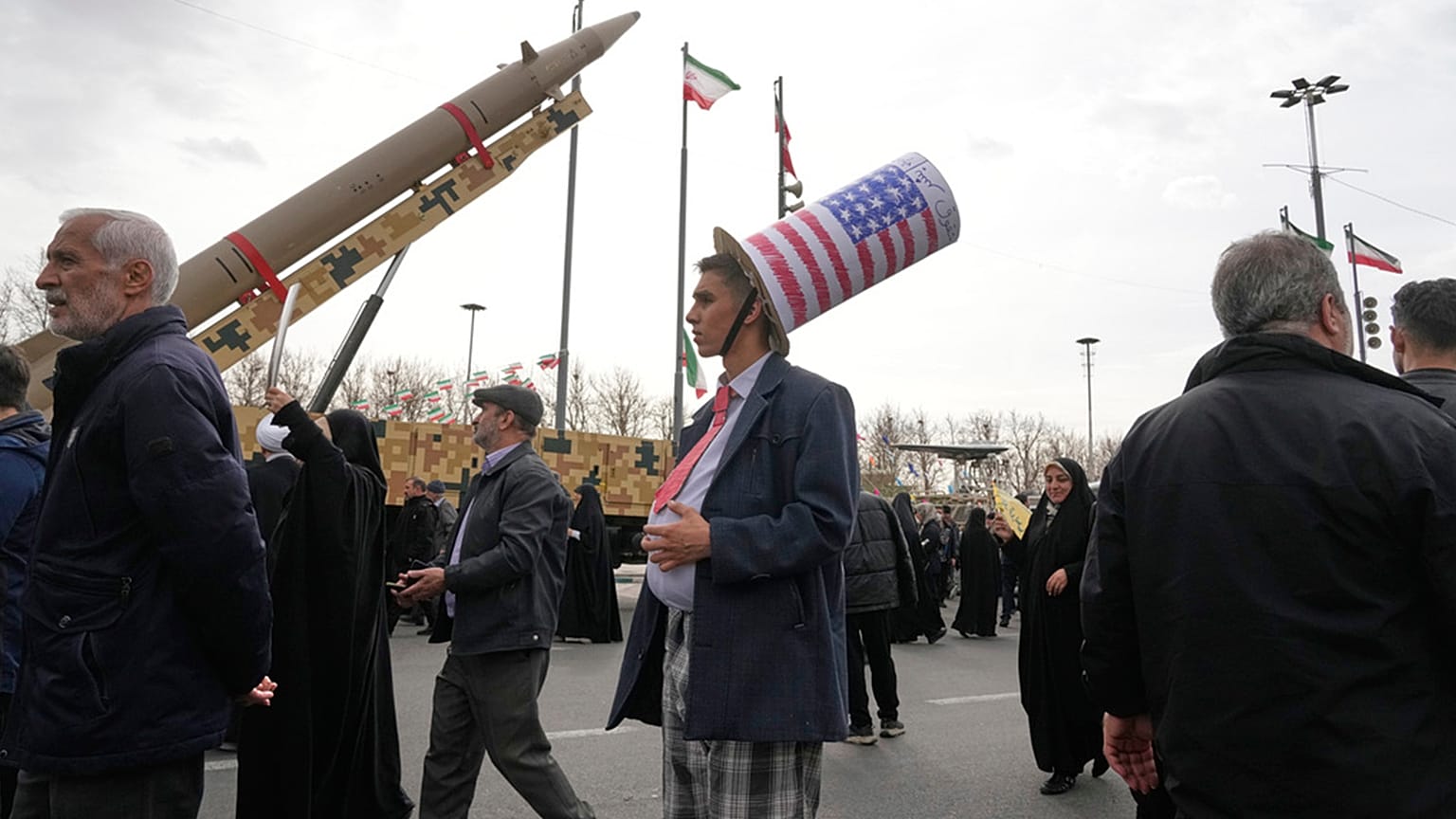 A man wears an Uncle Sam hat as he stands in front of an Iranian-built missile during a rally marking 1979 Islamic Revolution at the Freedom Sq in Tehran, 11 February 2026