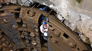 Μία εργαζόμενη βγαίνει μέσα από το ΤΒΜ ενώ η κεφαλή του μετροπόντικα "Αθηνά" προβάλλει από τη σήραγγα καθώς ρίχνει τα τελευταία χώματα, φτάνοντας στο φρέαρ του Ευαγγελισμού,