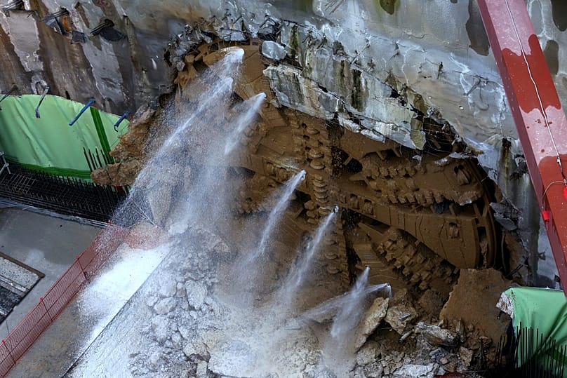 Η κεφαλή του μετροπόντικα "Αθηνά" προβάλλει απο τη σήραγγα καθώς ρίχνει τα τελευταία χώματα, φτάνοντας στο φρέαρ του Ευαγγελισμού