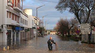 FILE:Police officers evacuate residents from a hotel by inflatable boat along a flooded street after the Sado River overflowed following heavy rains in Alcácer do Sal