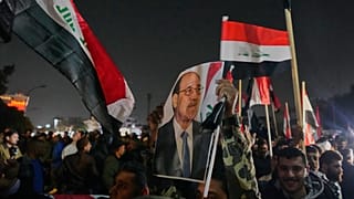 رجل عراقي يحمل صورة رئيس الوزراء السابق نوري المالكي، خلال احتجاج ضد الرئيس دونالد ترامب على جسر يؤدي إلى المنطقة الخضراء المحصنة حيث تقع السفارة الأمريكية في بغداد، 