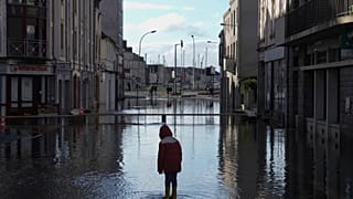 FILE: A boy stands in a flooded street as severe flooding hits western France amid storm Ivo, Thursday, Jan. 30, 2025
