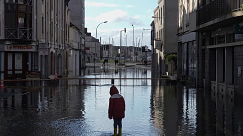 FILE - Un ragazzo in piedi in una strada allagata durante le gravi inondazioni nella Francia occidentale per la tempesta Ivo, giovedì 30 gennaio 2025