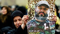 سيدة من أنصار حزب الله  ترفع صورةً للقائد البارز الراحل عماد مغنية، الضاحية الجنوبية لبيروت، لبنان، يوم الاثنين 16 فبراير/شباط 2009.