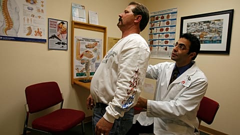 Lekarz badający plecy pacjenta w swojej klinice.