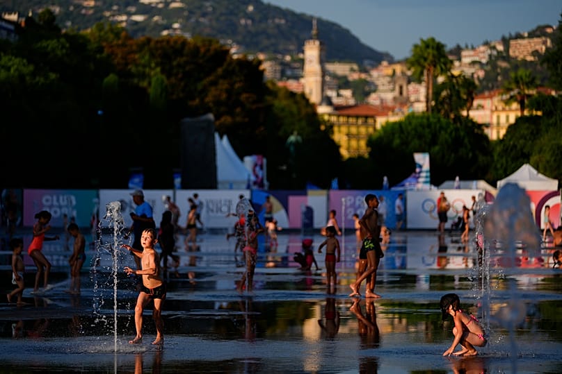 Children play at a splash fountain area near signage for the 2024 Summer Olympics in Nice, 23 July, 2024