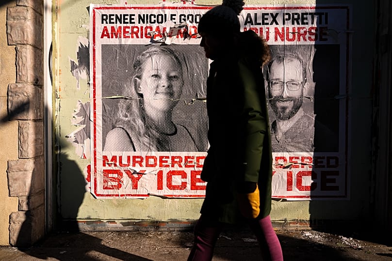 Egy nő Renee Good és Alex Pretti poszterei mellett sétál egy Prettiért rendezett szolidaritási kerékpártúra során, 2026. január 31-én, Minneapolisban