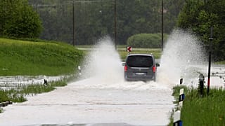 Auto fährt durch überflutete Straße in der Nähe von Marquartstein, 21. Mai 2019