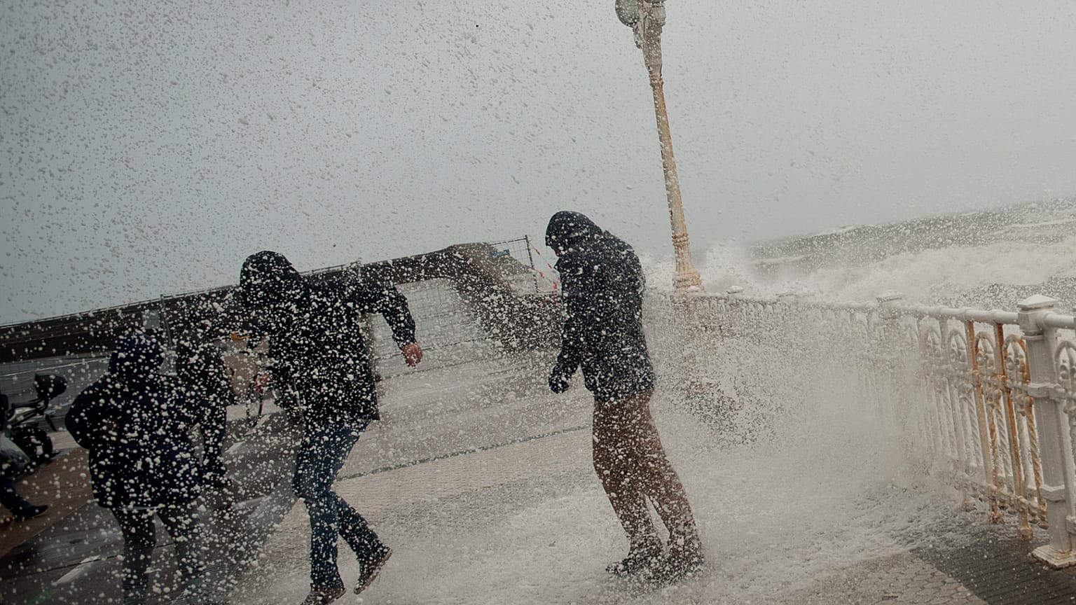 ARCHIVO: La gente corre mientras intenta protegerse del agua en el Paseo Nuevo durante la marea alta, en San Sebastián, norte de España, el viernes 30 de enero de 2015. 