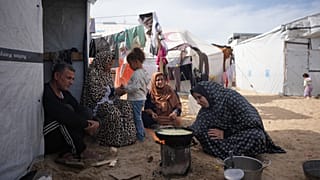 تقوم سهام عمران (54 عامًا)، التي عادت مؤخرًا من مصر بعد استكمال علاج طبي، بطهي الطعام على نار مكشوفة بجانب خيمتها في خان يونس جنوب قطاع غزة، يوم السبت 7 فبراير/شباط 2026.