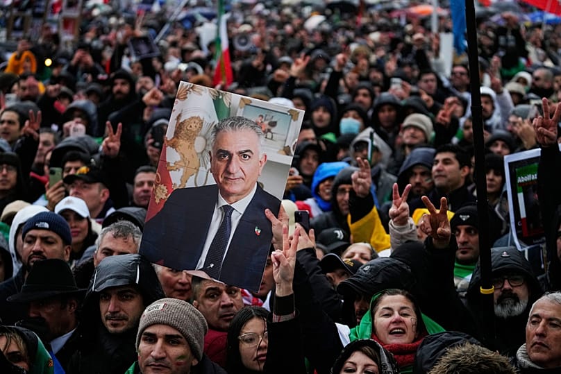 Des partisans du prince héritier iranien en exil, Reza Pahlavi, brandissent une affiche à son effigie lors d'une manifestation pendant la Conférence de Munich.
