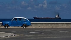 Ein amerikanischer Oldtimer fährt an der Strandpromenade entlang, während ein Tankwagen Havanna, Kuba, verlässt, 