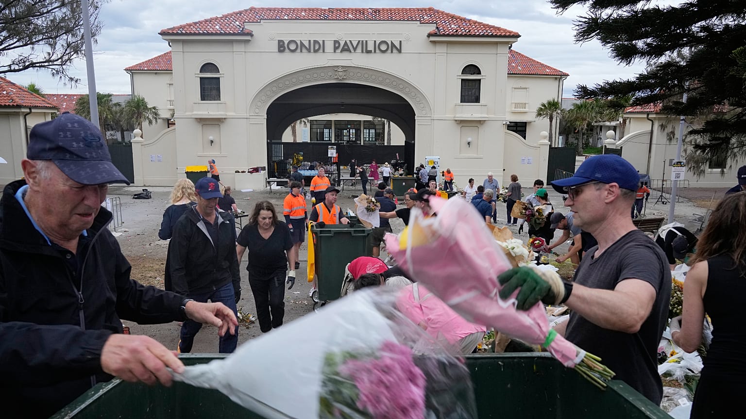 يتجمع عمّال لجمع الزهور ورسائل الدعم والأغراض التي تُركت كنصب تذكاري أثناء تفكيكه في سيدني، يوم الاثنين 22 ديسمبر/كانون الأول 2025، بعد أسبوع من هجوم استهدف مهرجانًا يهوديًا 