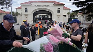 يتجمع عمّال لجمع الزهور ورسائل الدعم والأغراض التي تُركت كنصب تذكاري أثناء تفكيكه في سيدني، يوم الاثنين 22 ديسمبر/كانون الأول 2025، بعد أسبوع من هجوم استهدف مهرجانًا يهوديًا 